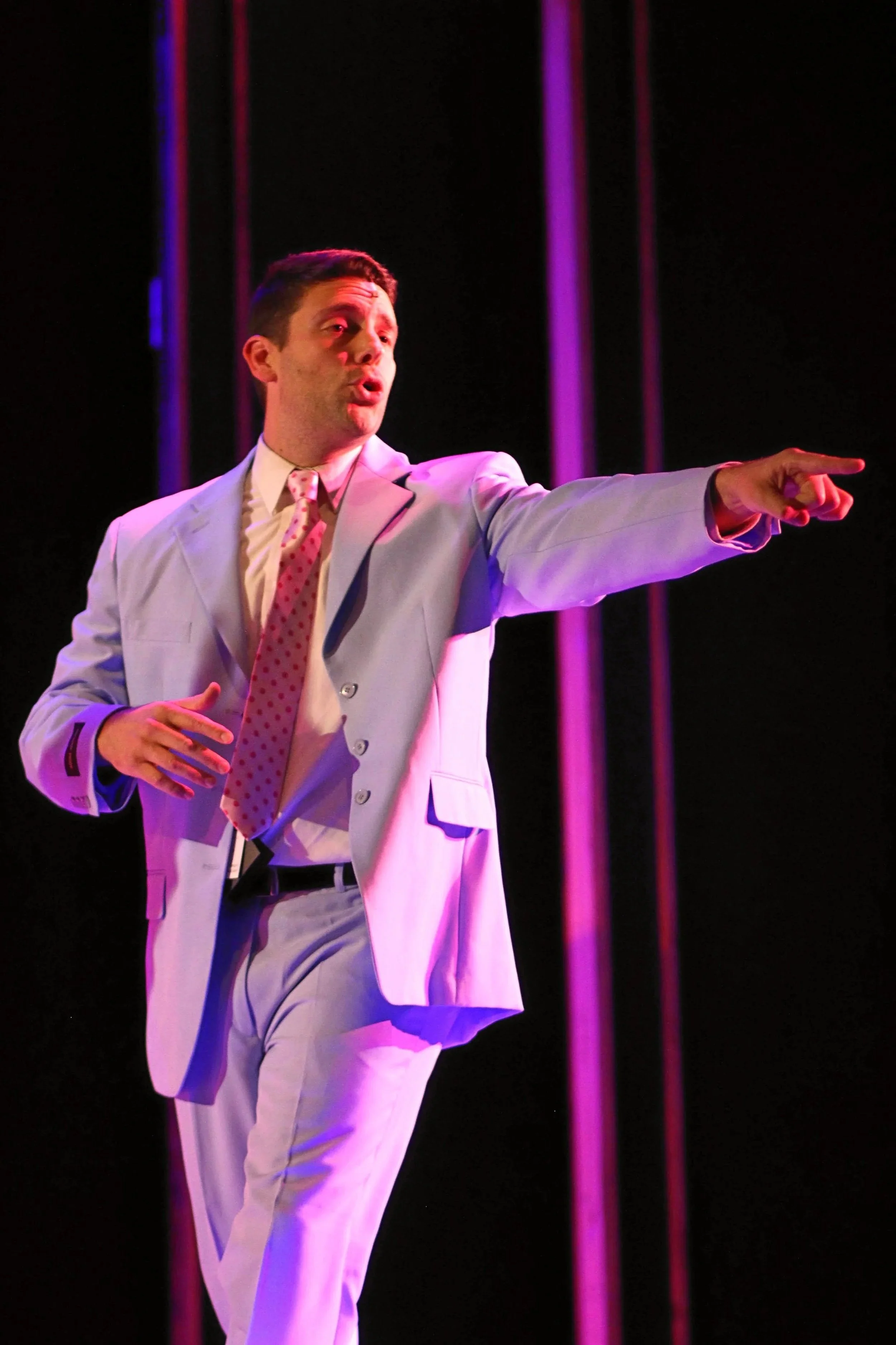 Michael Mingoia performing on stage in a periwinkle suit, showcasing his professional theater and performance background